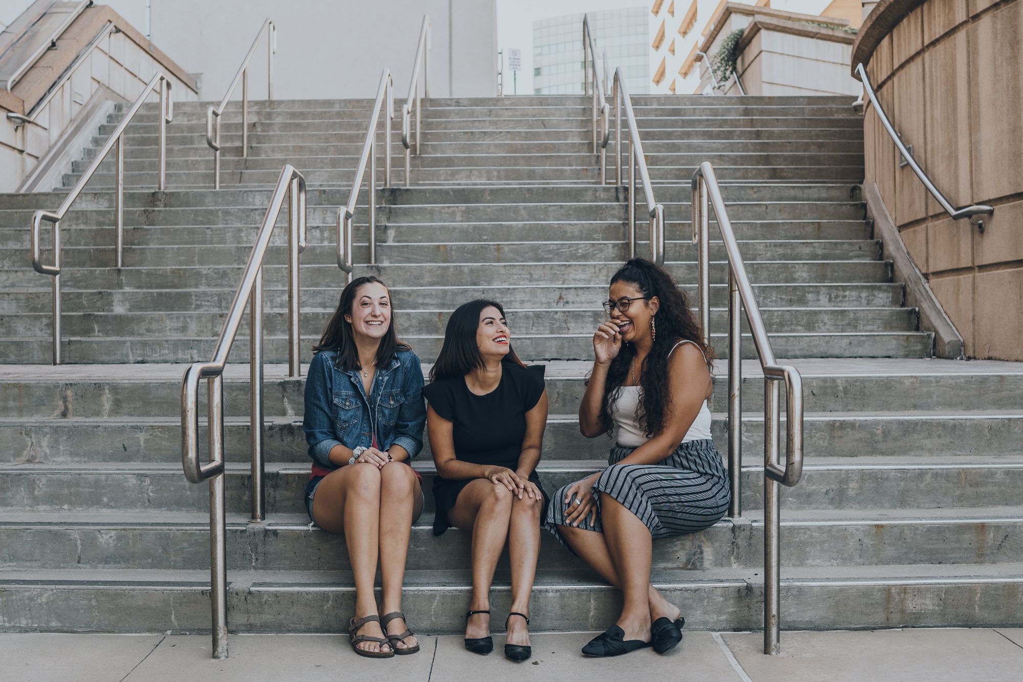 three-women-smiling-while-sitting-on-stairs (1)